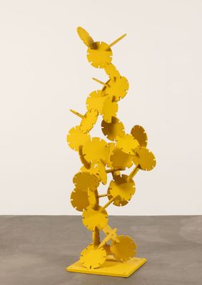 une sculpture jaune représentant des fleurs, posée sur un socle en bois
