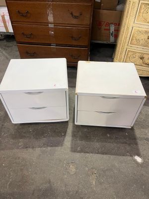 deux tables de chevet blanches à tiroirs et une commode à l'arrière-plan