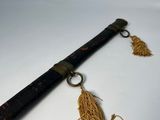 a very long wooden stick with a tassel hanging from it