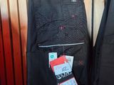 two pairs of pants hanging on a rack in front of a wooden wall