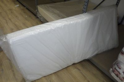 Des cartons contenant des matelas sont empilés les uns sur les autres dans une pièce