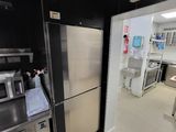 réfrigérateur en acier inoxydable dans une cuisine professionnelle équipée de plans de travail en acier inoxydable