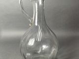 a clear glass pitcher with a handle on a table