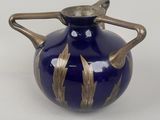 un vase bleu orné de motifs dorés sur fond blanc