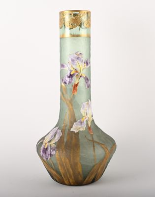 un vase vert orné de fleurs violettes sur fond blanc