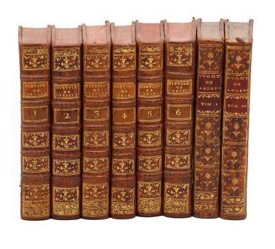 six vieux livres alignés sur une surface blanche