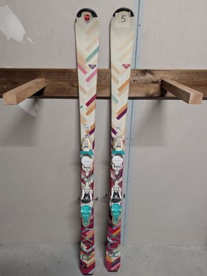 une paire de skis posée sur une étagère en bois près d'un mur