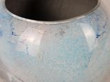 a close up of a blue vase with a silver rim