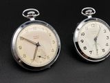 two clocks sitting side by side on a black surface