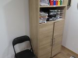 a table with a chair and a book shelf in the corner