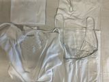 a lot of white clothing on a bed next to a bottle of water