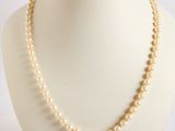 pearl necklace on a mannequin display with a white background