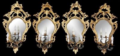 Trois miroirs aux cadres dorés sont accrochés à un mur noir.