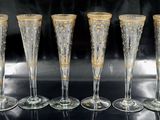 four champagne flutes with gold designs on them sitting on a table