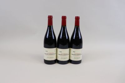 trois bouteilles de vin rouge sont posées sur une surface blanche