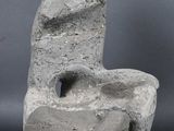 sculpture of a man sitting on a rock on a gray surface