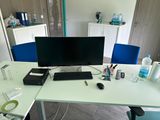 a desk with a computer, keyboard, mouse, and other items on it