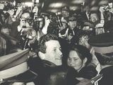 photographie en noir et blanc d'une foule de personnes brandissant des bouteilles de bière