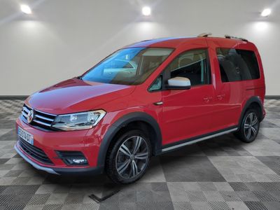 Une VW Tourer rouge est garée dans une pièce au sol à carreaux.