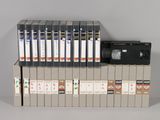 a stack of dvds and a cassette player on top of a box