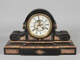 une horloge noire et dorée posée sur un socle, avec des chiffres romains
