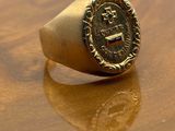 an image of a gold signet ring with a coin on it