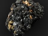 un morceau de minéral noir et doré posé sur une surface noire