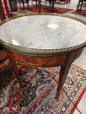 une table ancienne au plateau en marbre posée sur un tapis dans une pièce