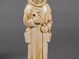 two carved ivory figurines of a monk holding a book