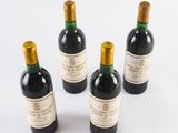 four bottles of wine are lined up on a white surface