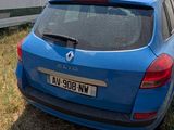 a blue car parked in a field with a trailer in the background