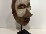 an image of a wooden mask on a stand on a white surface