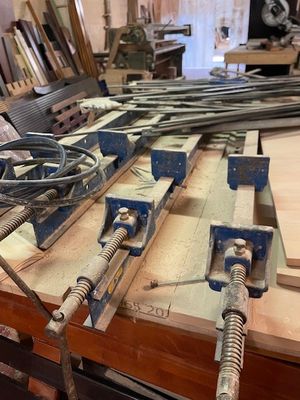 Plusieurs morceaux de bois sont posés sur un établi dans un atelier de menuiserie