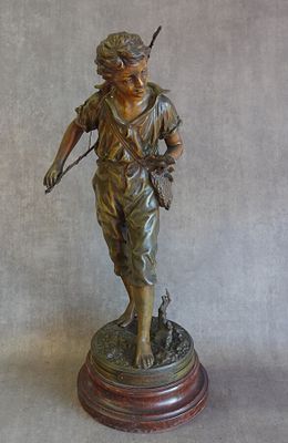 statue en bronze représentant un garçon muni d'un arc et de flèches, posée sur un socle