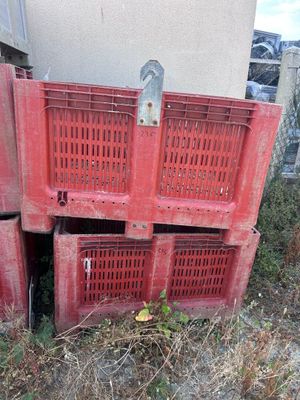 Plusieurs caisses rouges sont empilées les unes sur les autres dans l'herbe