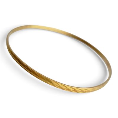 un gros plan d'un bracelet rigide en or sur fond blanc