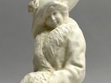 a white statue of a man sitting on a rock with a hat on