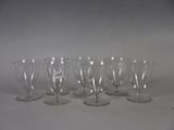 six wine glasses are lined up on a white surface