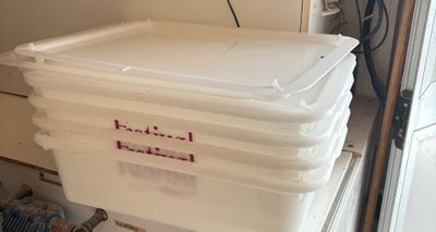 a stack of plastic containers sitting on top of a refrigerator