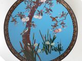 a round mirror with a painting of a tree and flowers on it