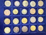 an assortment of gold coins in a display case on a blue surface