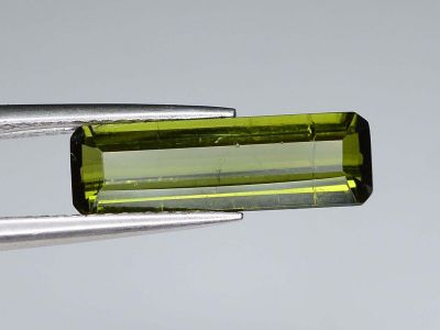 des tourmalines vertes tenues par une paire de pinces