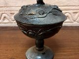 a metal bowl with a bird on it on a wooden table