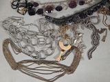 many different types of necklaces and bracelets laid out on a table