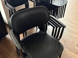 Plusieurs chaises en plastique noir sont alignées dans une pièce