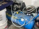 un compresseur d'air bleu posé par terre à côté d'un seau de peinture