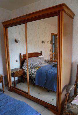 un lit et une chaise dans une chambre équipée d'un grand miroir