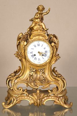 une horloge en or posée sur une table, surmontée d'une statue