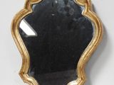 une image représentant un miroir à cadre doré posé sur un mur blanc