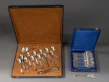 un service d'argenterie dans un coffret bleu et un ensemble de cuillères en argent dans un coffret bleu